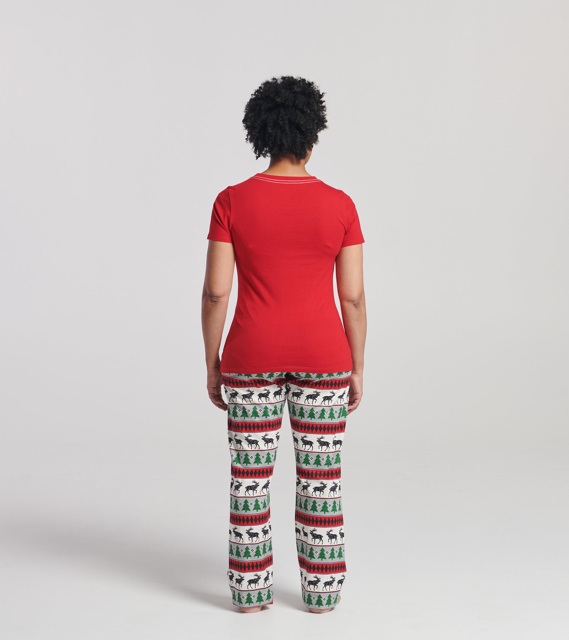 Red short sleeve t-shirt worn with patterned pajama pants featuring trees and reindeer, viewed from the back.