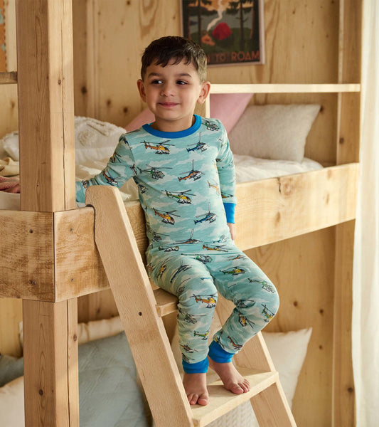 Light blue pajama set featuring colorful helicopter prints, with long sleeves and pants, worn by a boy on a bunk bed ladder.