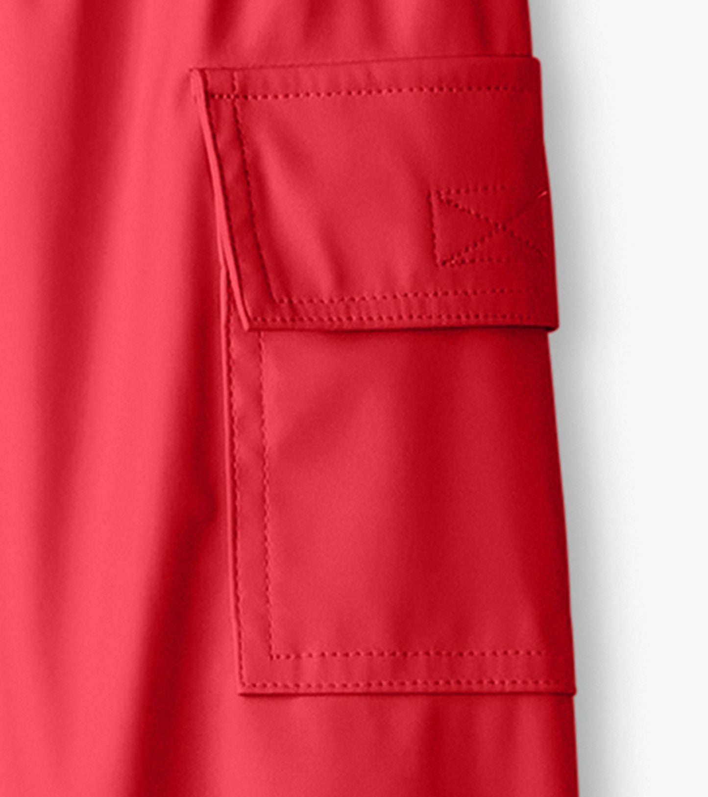 Red waterproof kids' rain pants featuring a side pocket and smooth finish, ideal for outdoor play in wet weather.