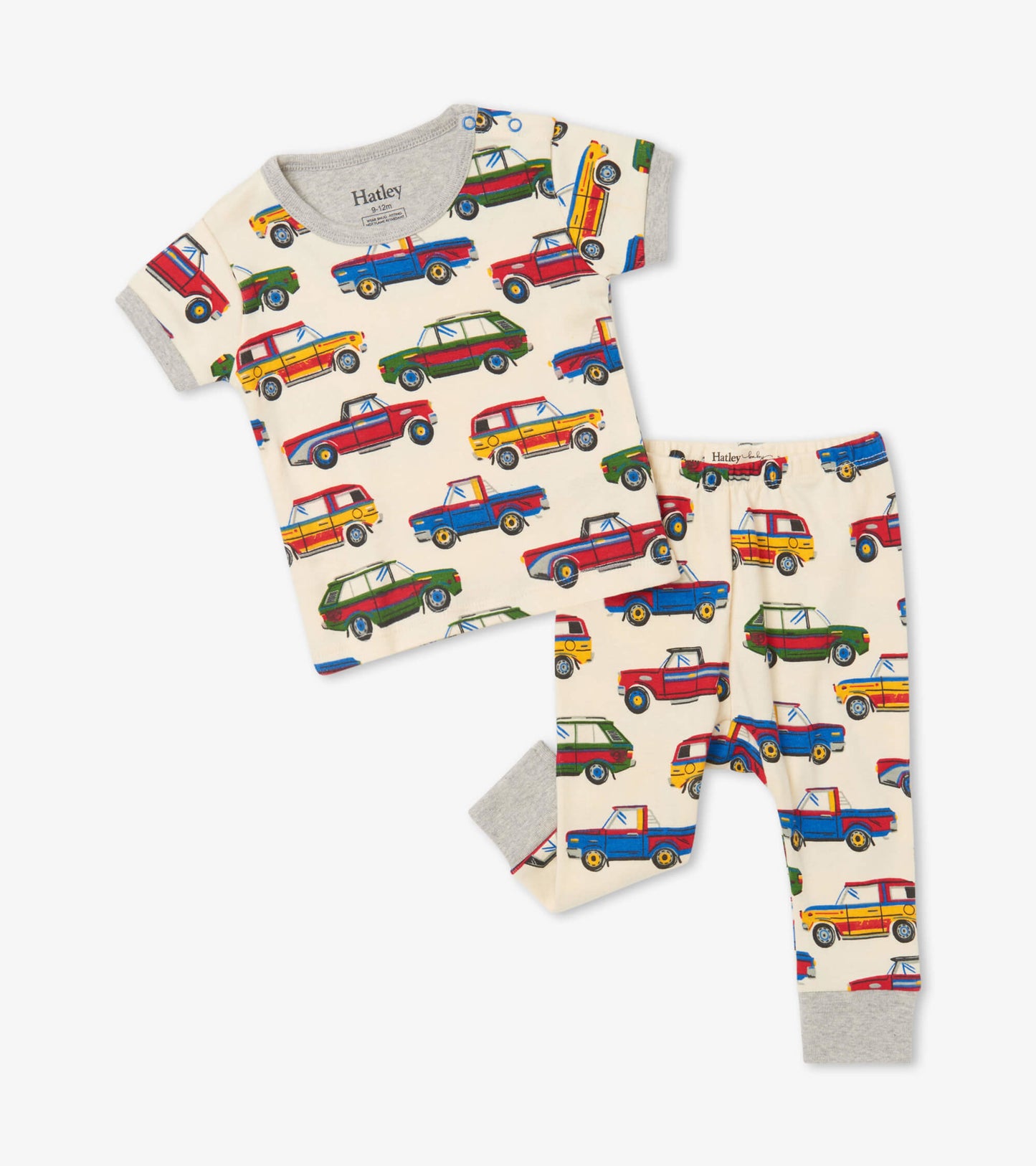 Organic cotton baby pajama set featuring colorful vintage cars on a cream background, short sleeves, and matching pants.