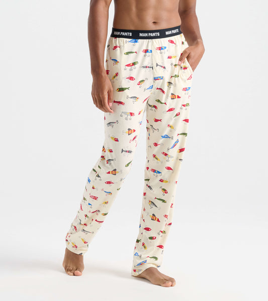 Beige pajama pants featuring colorful fishing lure patterns, with an elastic waistband labeled "MAN PANTS.