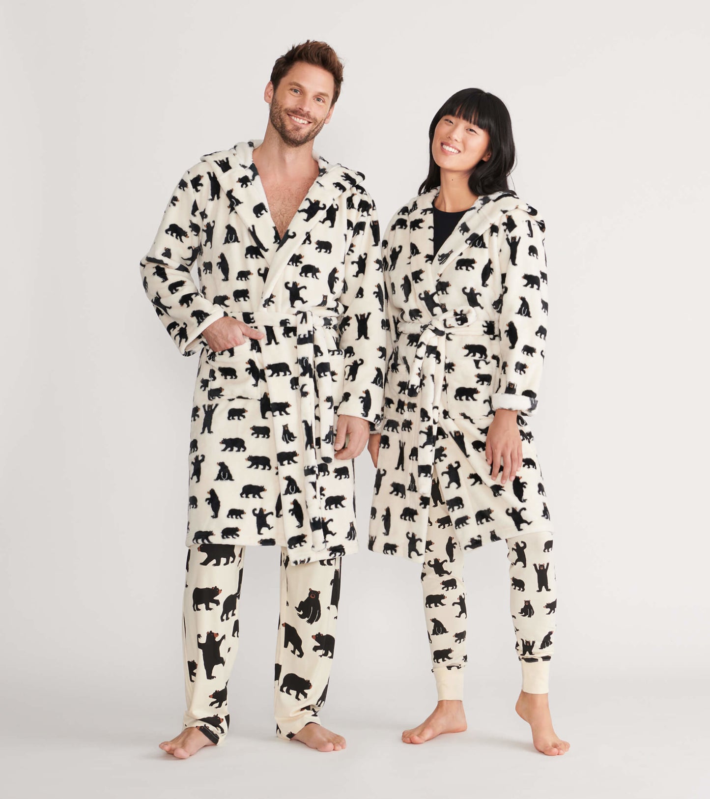 Black fleece robe featuring black bear patterns, worn by a man and woman, with a tie belt and hood.
