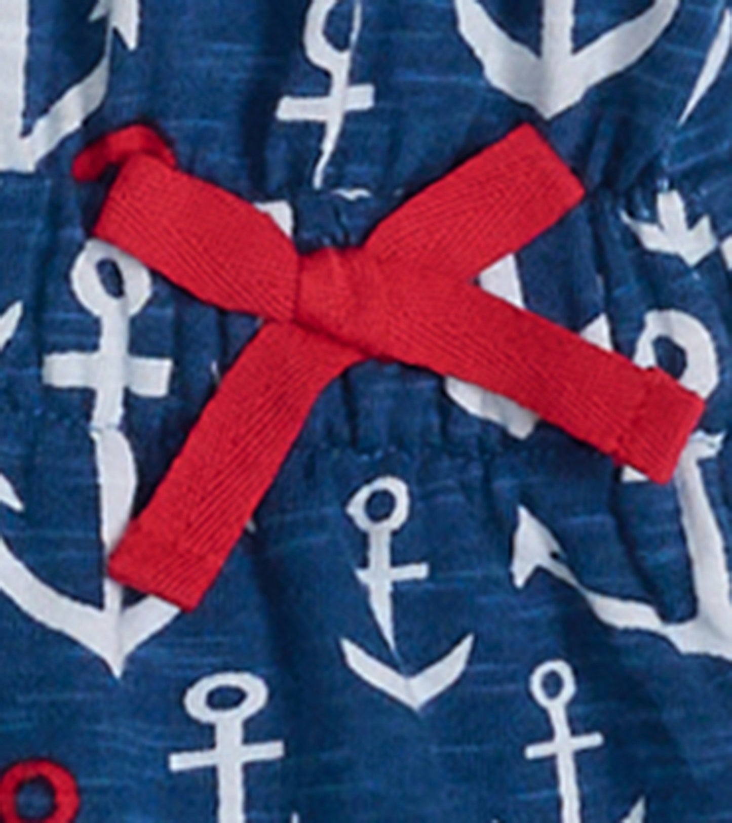 Navy t-shirt dress featuring white anchor pattern and a red bow detail at the waist.