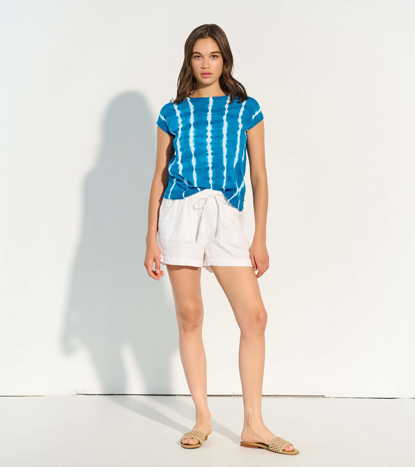 Blue tie-dye knit tee with short sleeves, paired with white shorts, styled for a casual summer look.