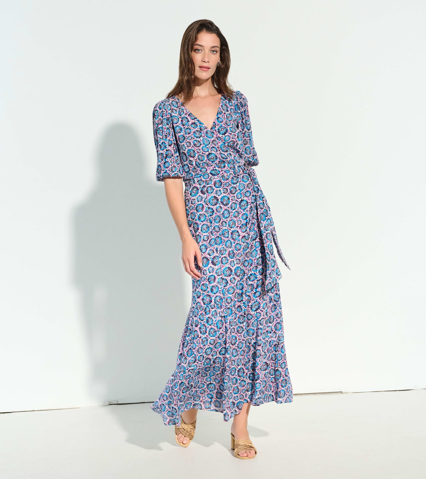 Blue and pink floral wrap dress with short puff sleeves and a tiered skirt, styled with beige heeled sandals.