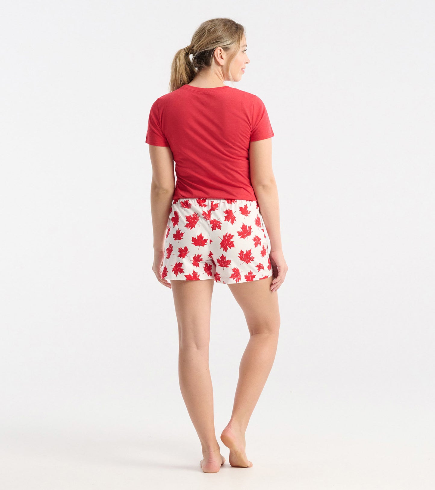 White cotton sleep shorts with red maple leaf pattern, featuring an elastic waistband, shown from the back.