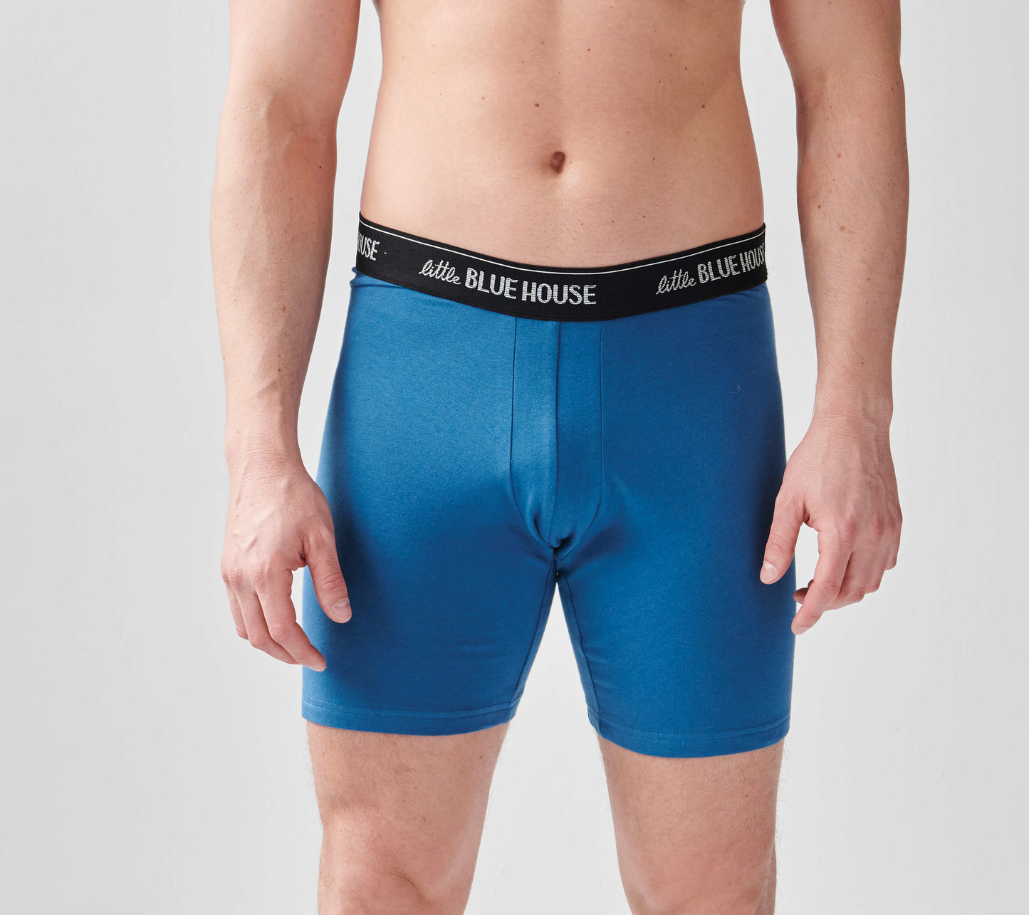 Blue boxer shorts with a black waistband, featuring a snug fit and smooth fabric, worn by a man.