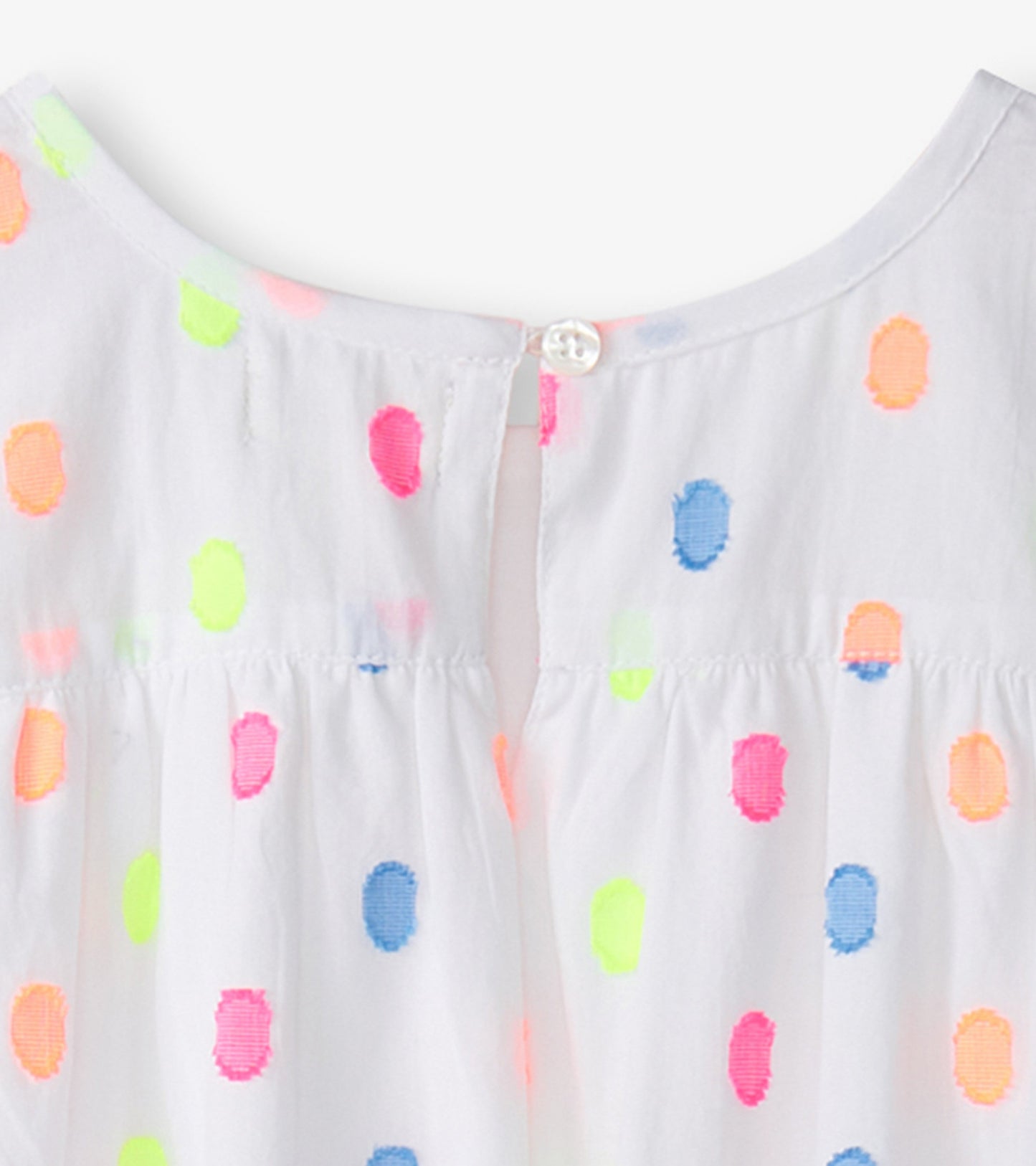 White woven play dress featuring colorful polka dots in neon pink, green, orange, and blue with a button closure at the back.