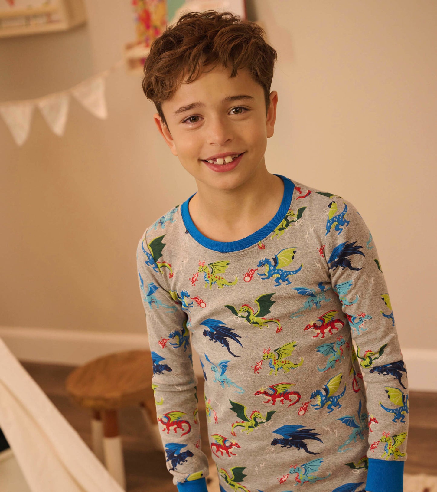 Gray organic cotton pajama set featuring colorful dragon patterns, with a blue crew neck and cuffs. Suitable for kids.