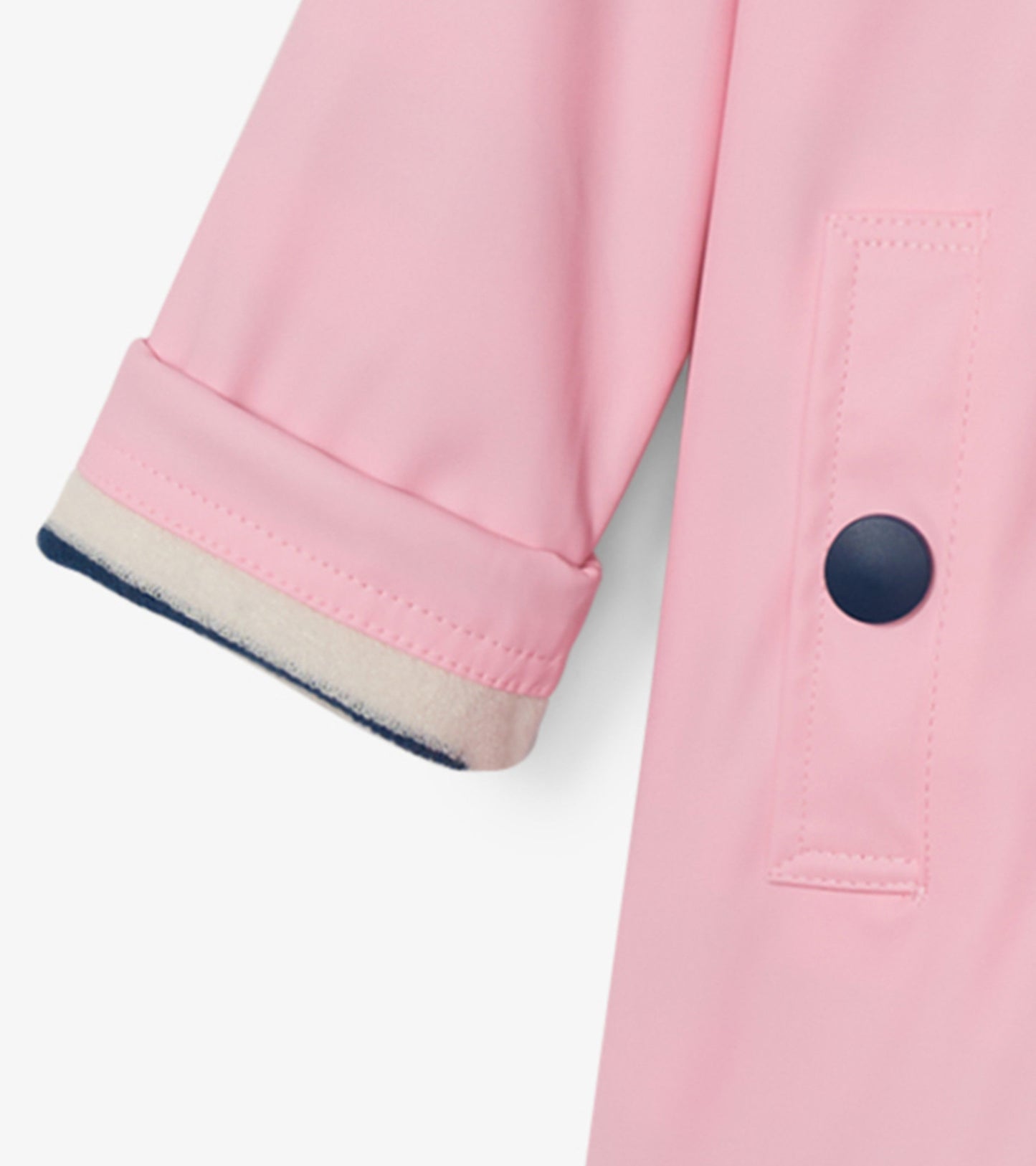 Pink rain jacket with navy trim, featuring a button-up design and rolled sleeves. Ideal for wet weather.