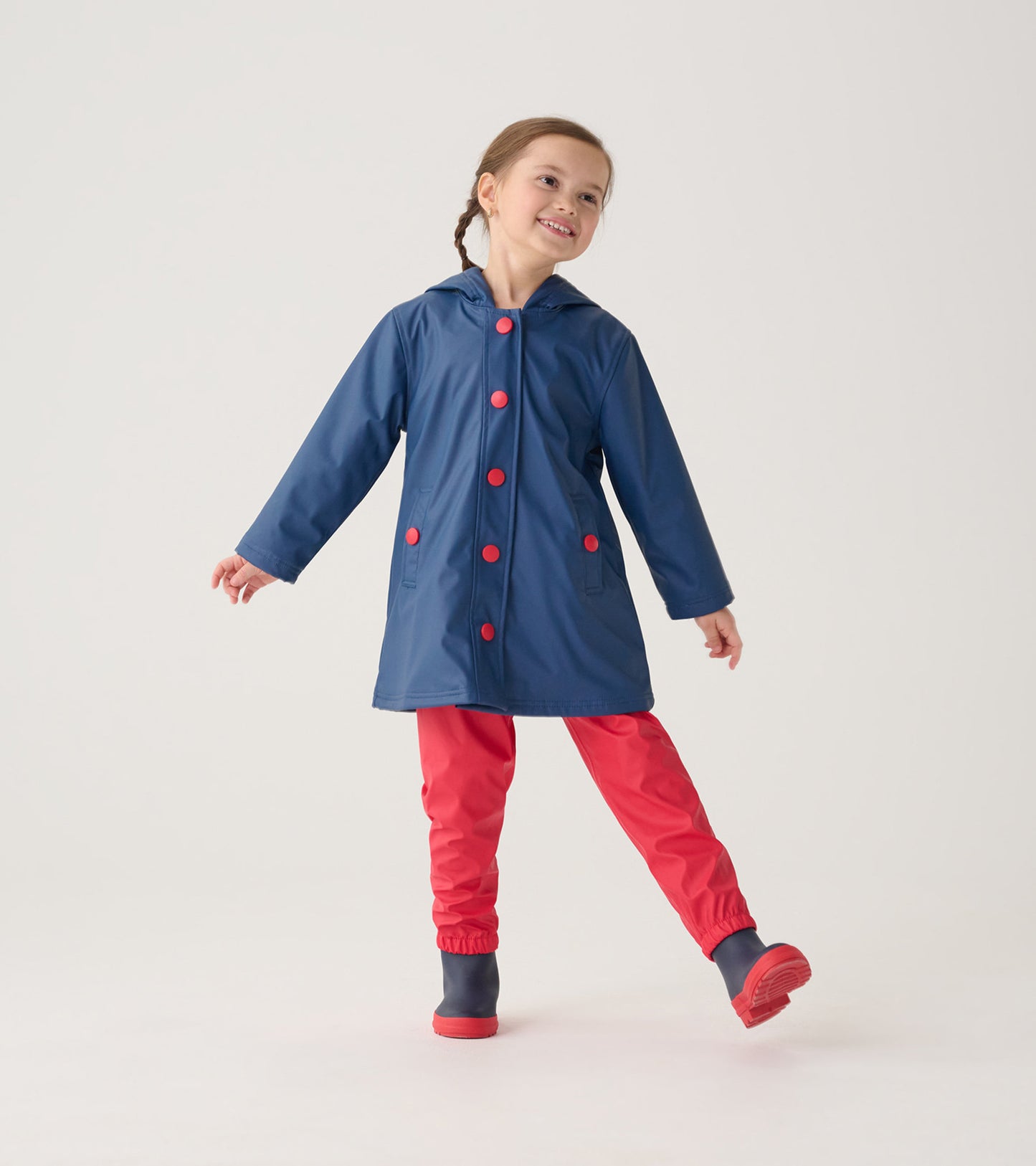 Red waterproof kids' rain pants with elastic cuffs, paired with a blue raincoat featuring red buttons.