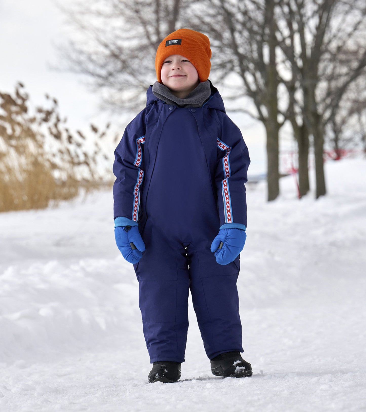 Navy toddler snowsuit with colorful side accents, worn by a child in a snowy outdoor setting, paired with blue gloves.