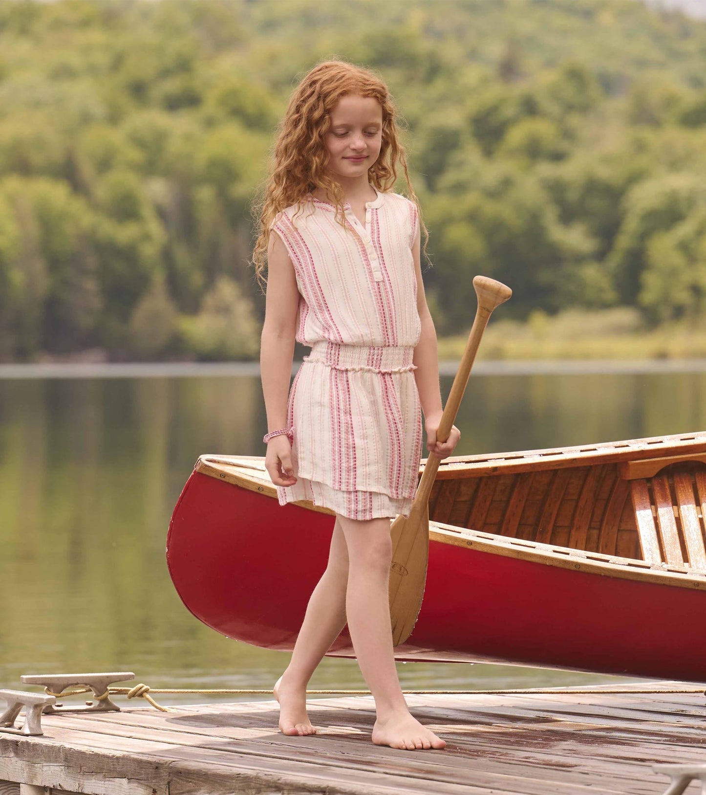 Girls' sleeveless dress with a smocked waist, featuring a pink and white stripe pattern, perfect for summer outings.