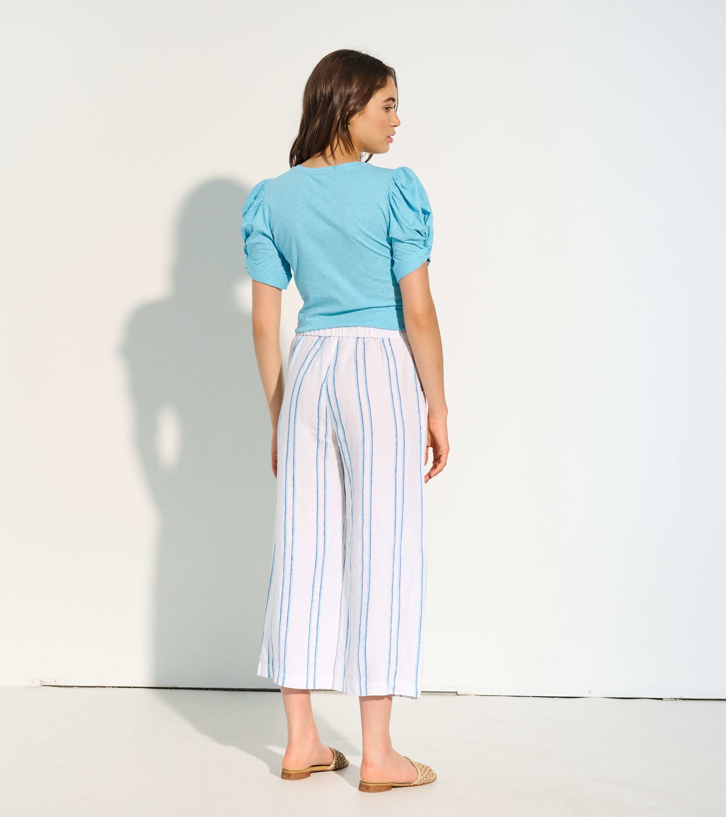 Cropped wide leg pants in white with blue stripes, featuring a relaxed fit and elastic waistband, shown from the back.