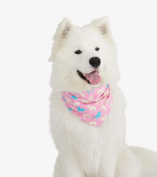 Reversible dog bandana in pink with colorful dog prints, worn around the neck of a white fluffy dog.