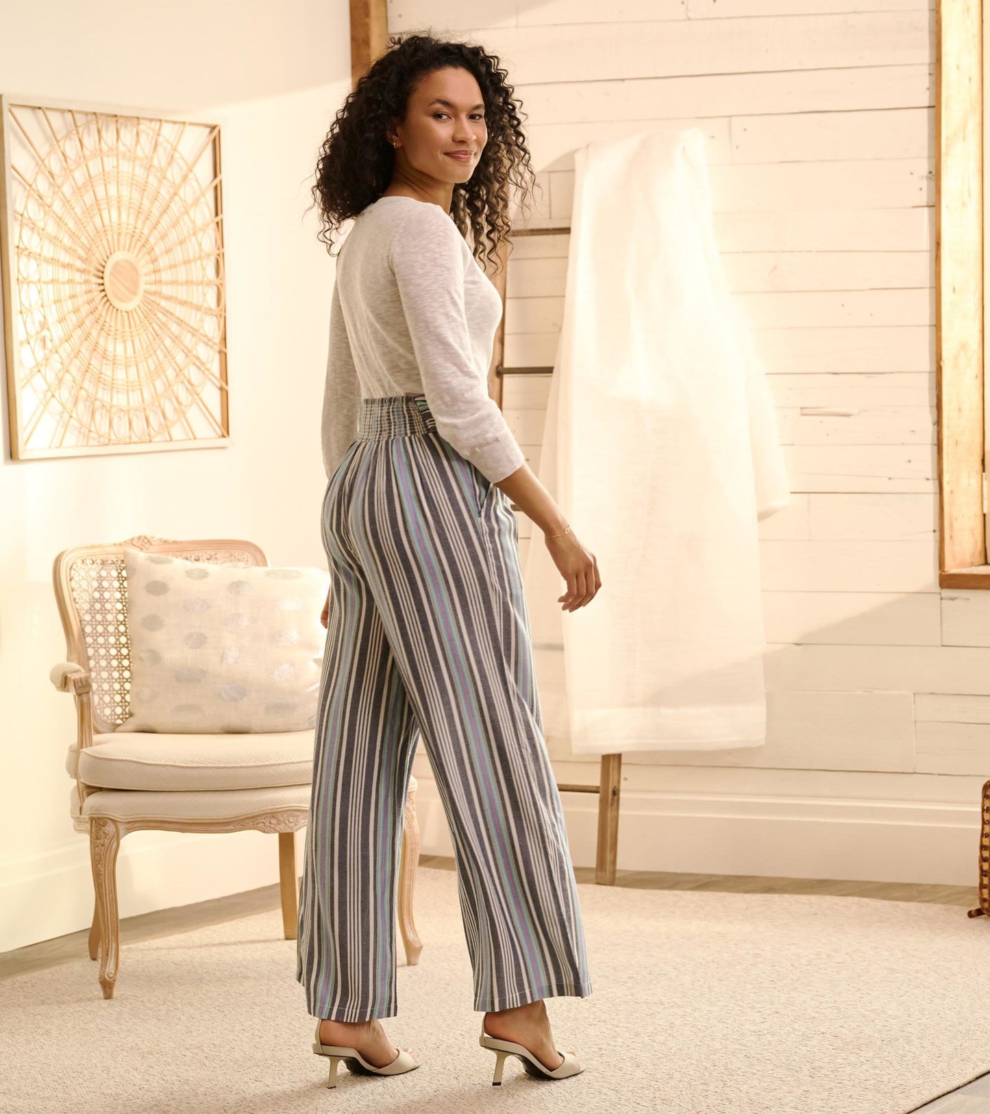 Belted wide leg pants featuring rainbow stripes, shown from the back with a relaxed fit and high waist.