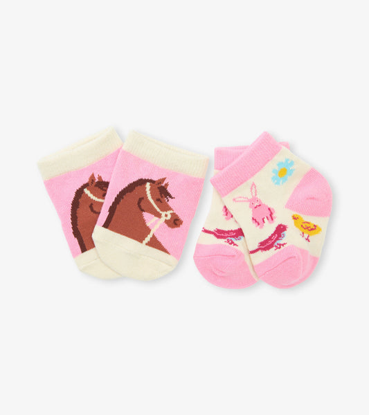 Two pairs of baby socks: one with a horse design on pink, the other featuring a bunny and flowers on cream and pink.