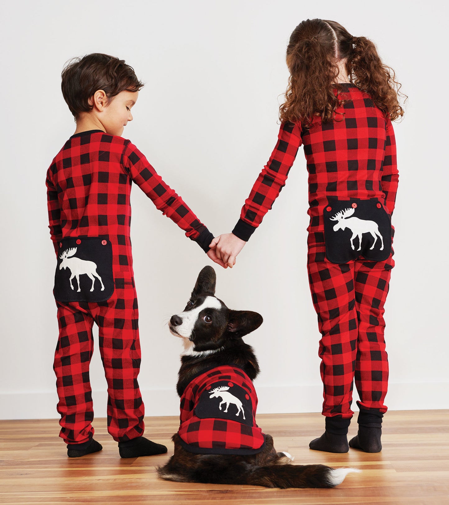 Red plaid kids' onesie featuring a moose design on the back, worn by two children holding hands with a dog.