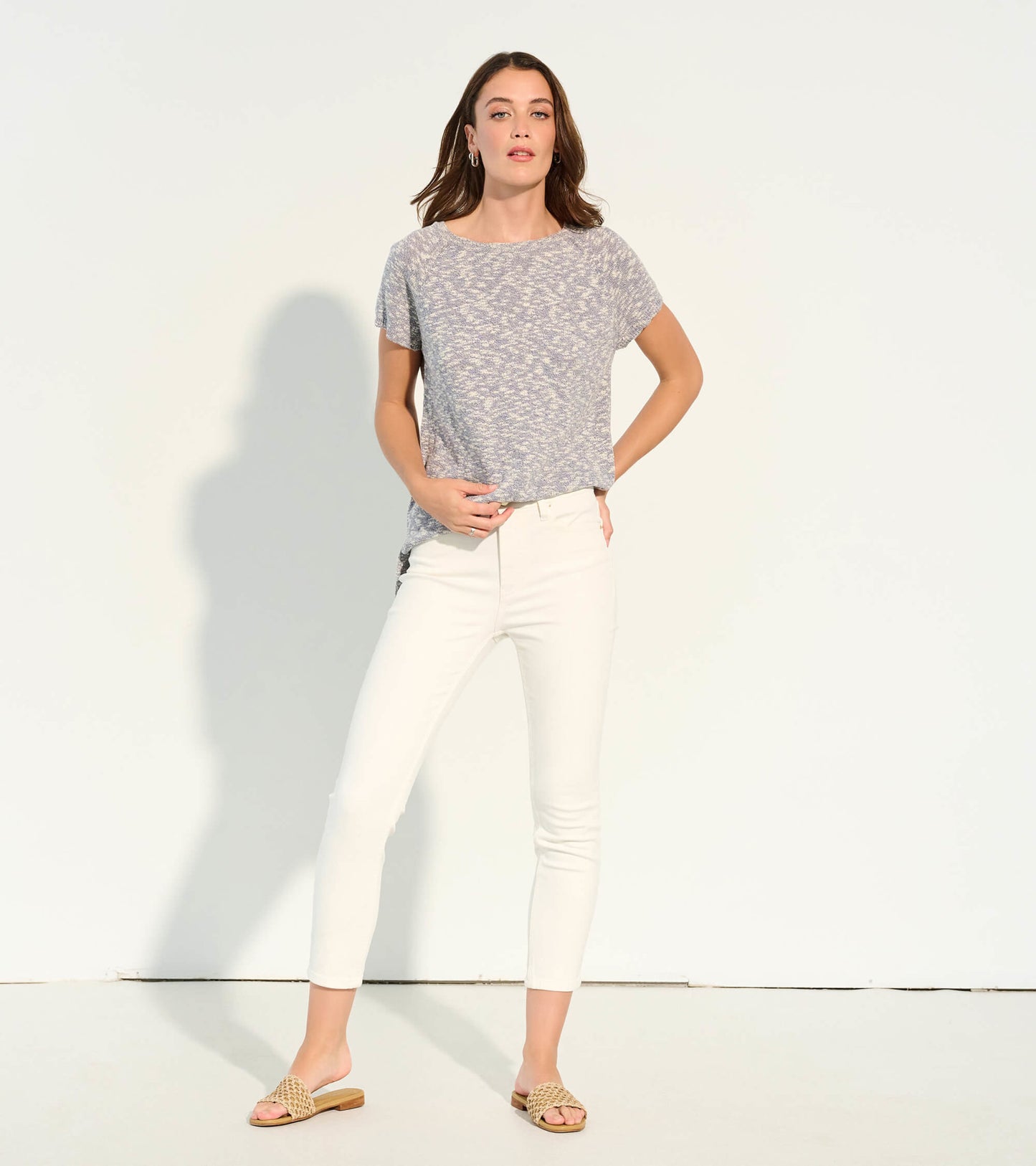 Light gray knit tee with a subtle pattern, short sleeves, and a relaxed fit, paired with white pants.