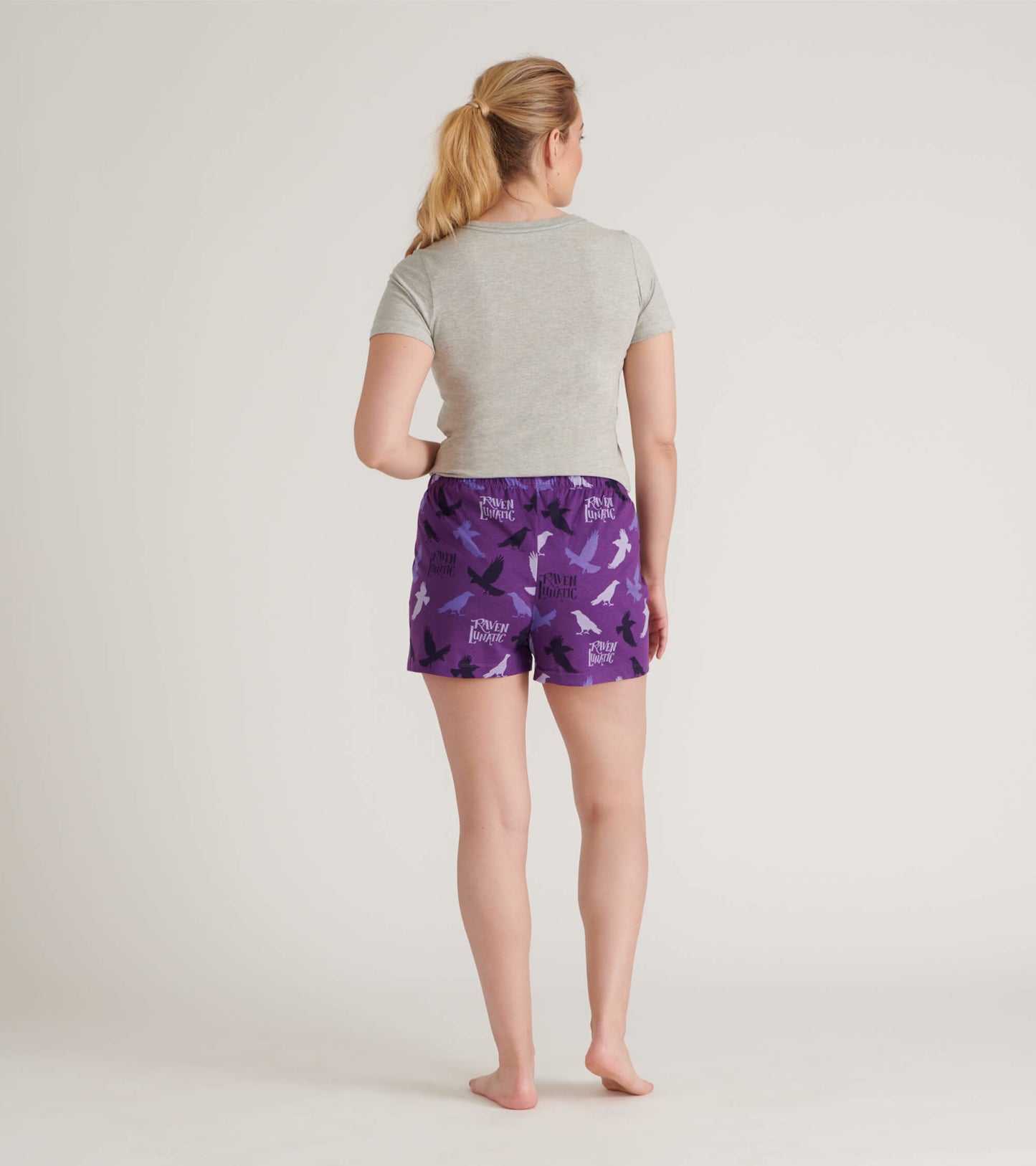 Purple cotton sleep shorts featuring a bird pattern, shown from the back with a gray top.