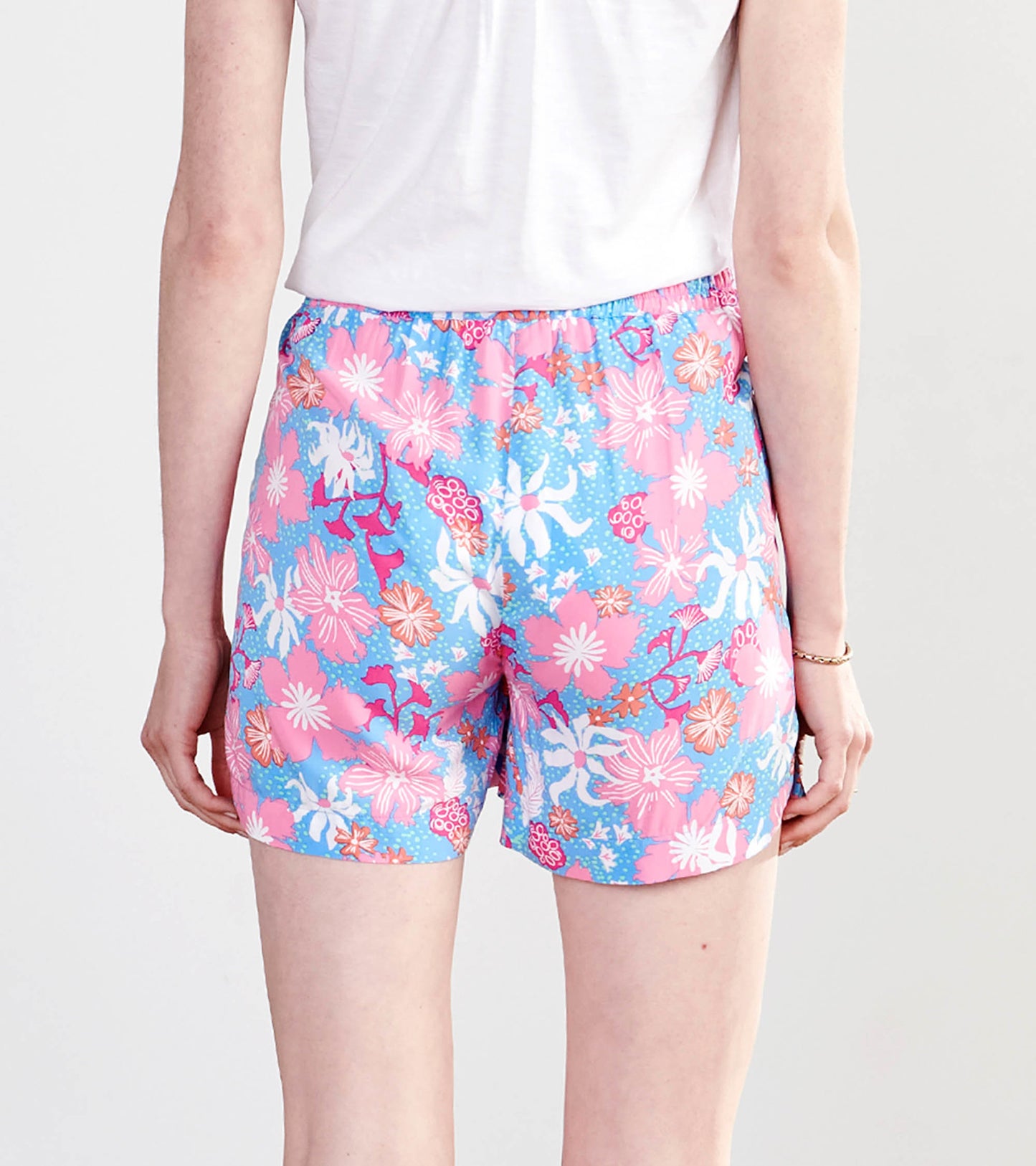 Colorful floral-patterned shorts in pink and blue, featuring an elastic waistband, shown from the back.