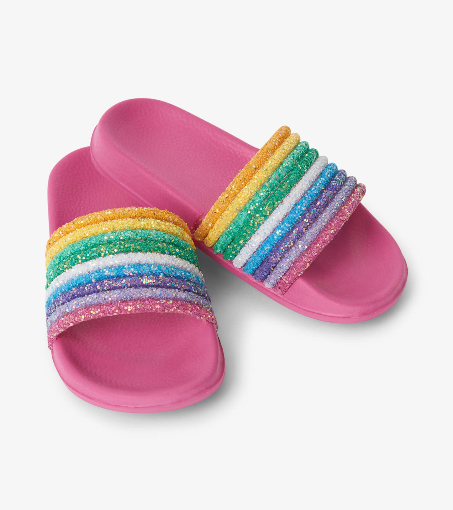 Pink slides featuring a glittery rainbow strap with multiple colorful bands. Ideal for casual summer wear.