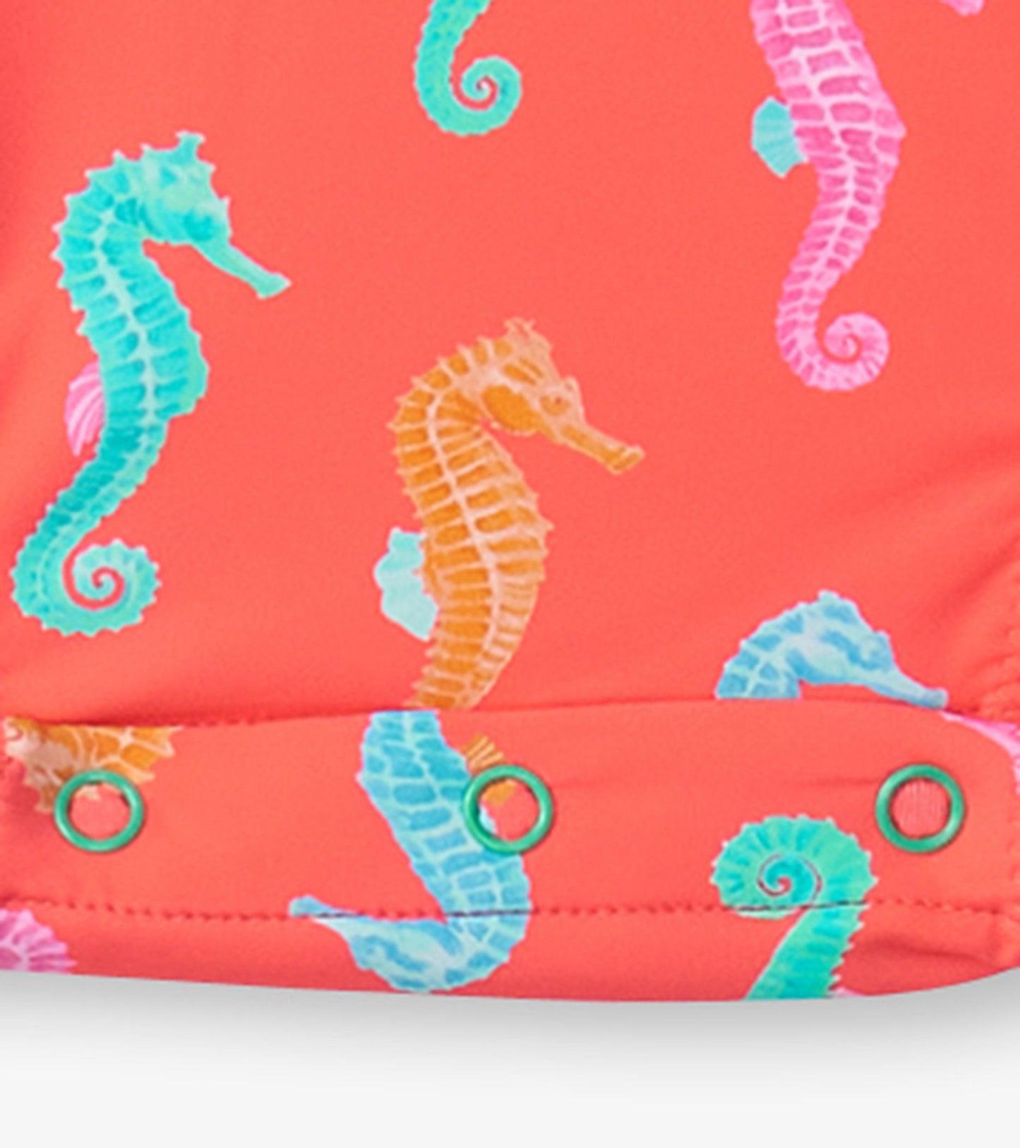 Coral rashguard swimsuit featuring colorful seahorse patterns and snap closures at the bottom for easy dressing.