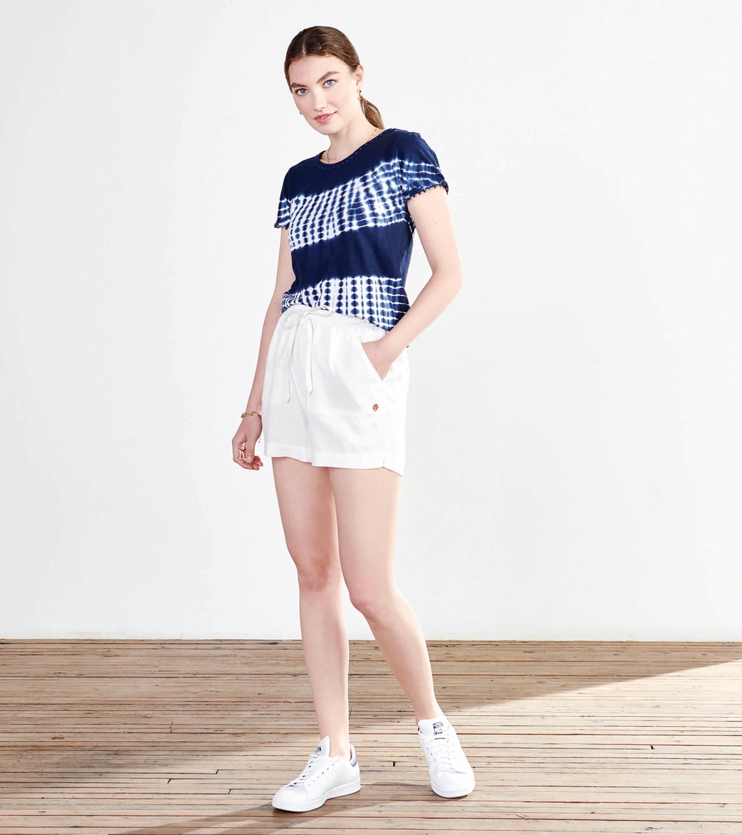 Navy and white tie-dye short-sleeve tee, paired with white shorts, styled casually with white sneakers.
