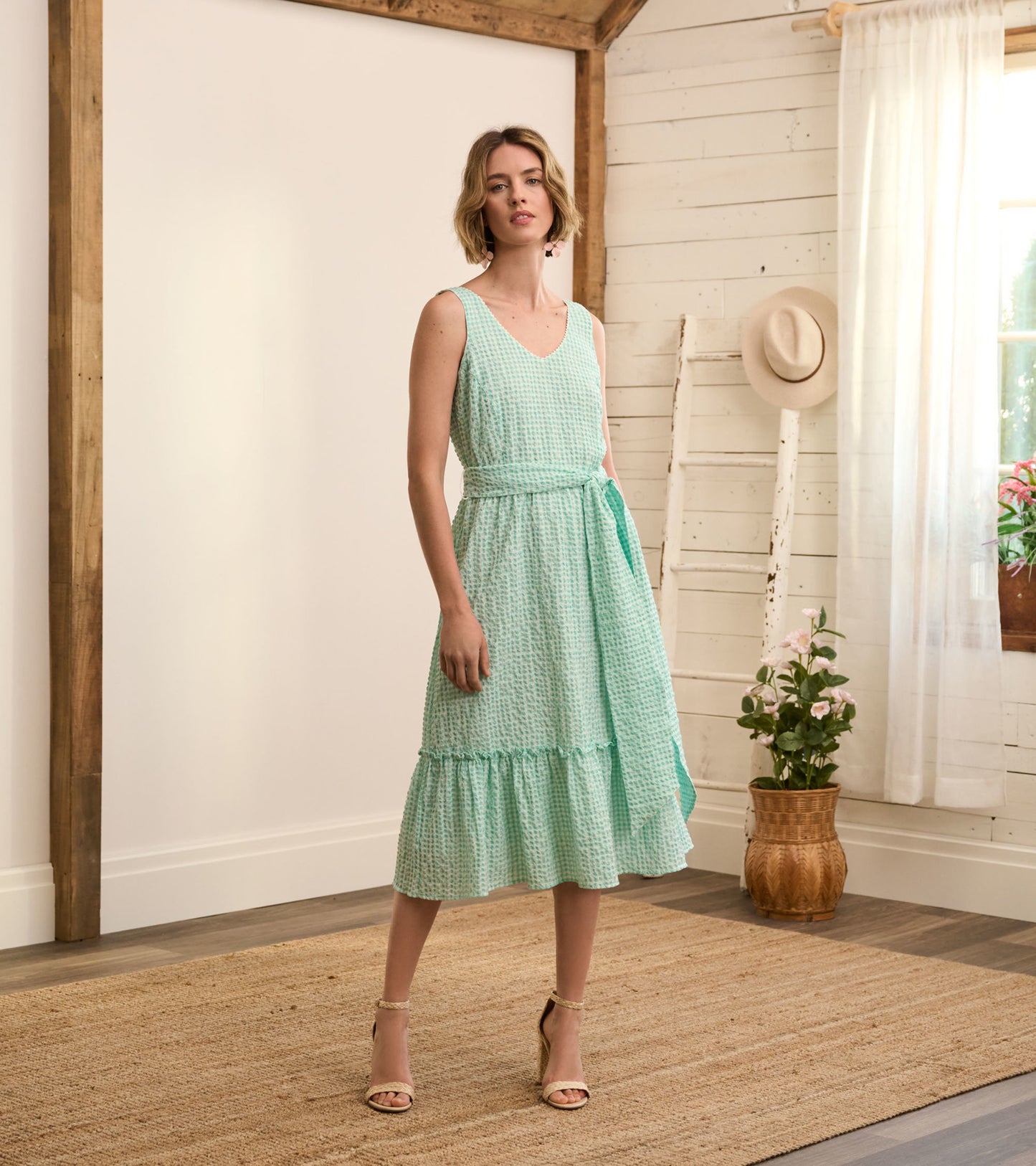 Mint green midi dress with a gingham pattern, sleeveless design, and a tied waist, featuring a tiered hem.