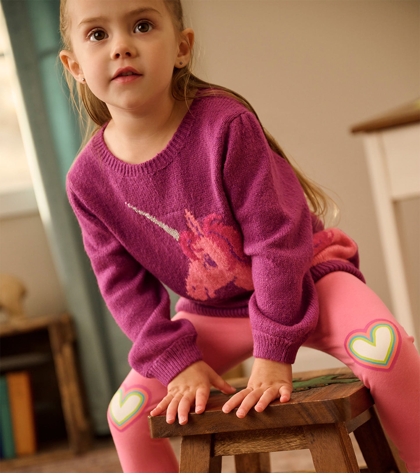 Purple sweater featuring a unicorn design, paired with pink leggings adorned with heart patches.