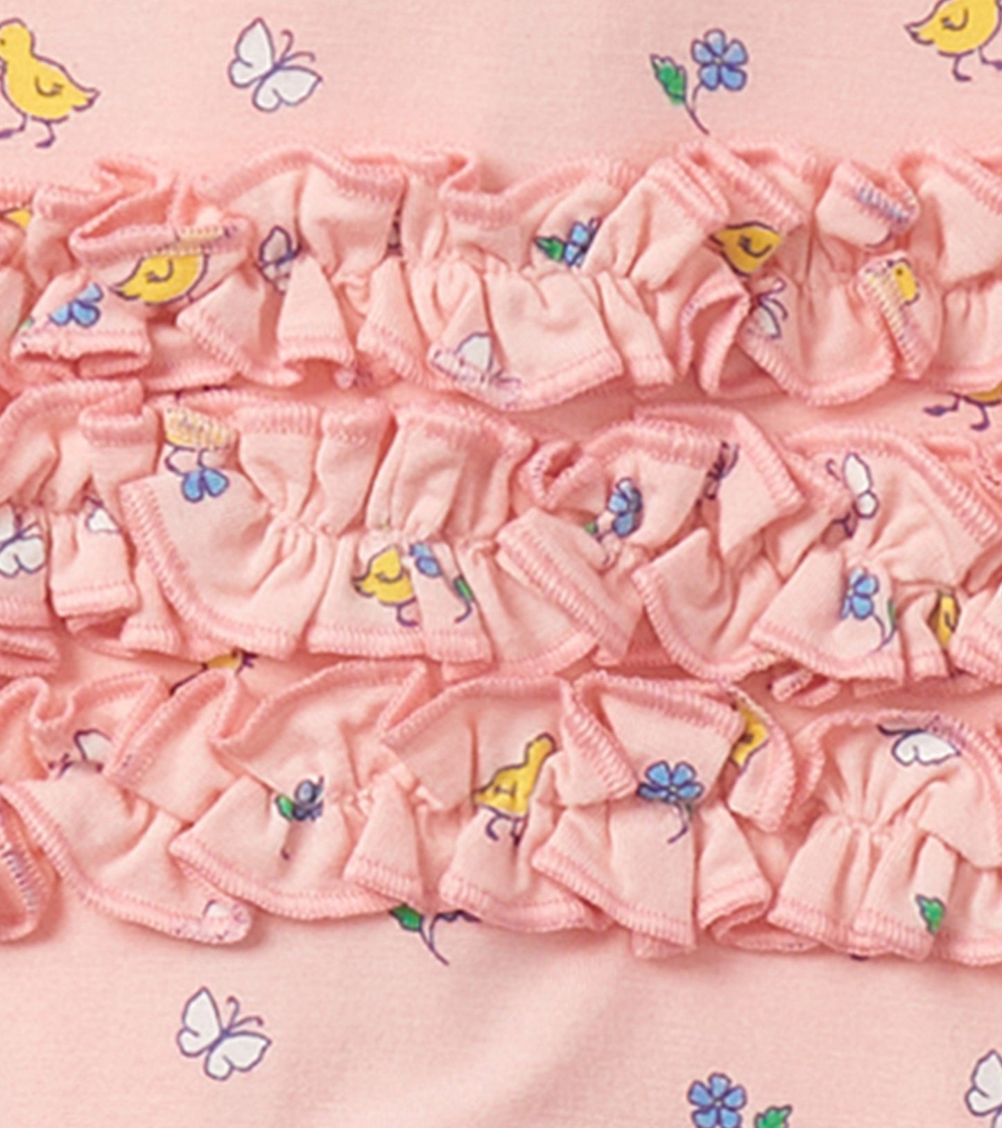 Pink footed sleeper with ruffle detailing, featuring yellow chicks and floral patterns, suitable for baby girls.
