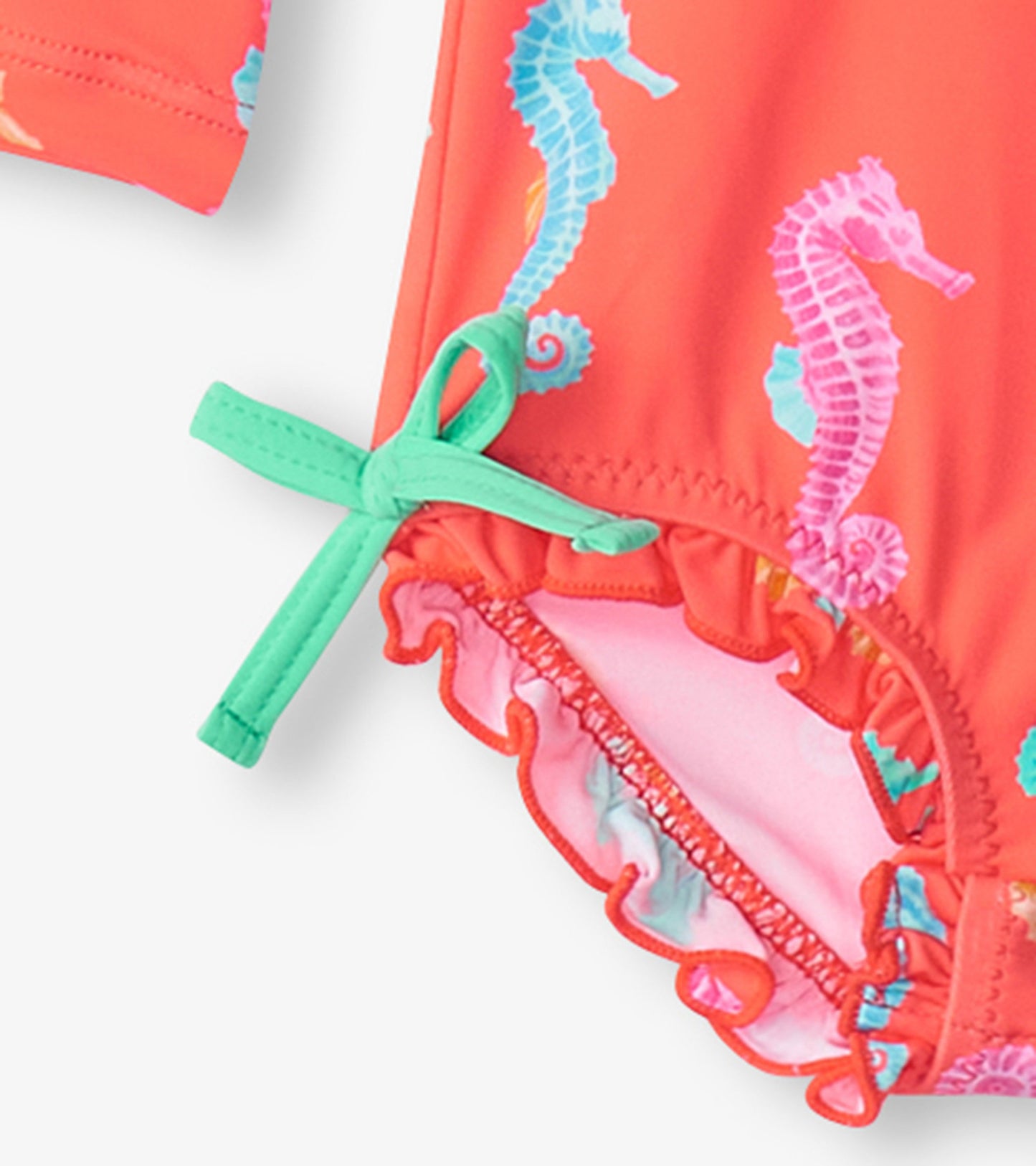 Coral rashguard swimsuit with colorful seahorse print and ruffled edges, featuring a mint green tie detail.