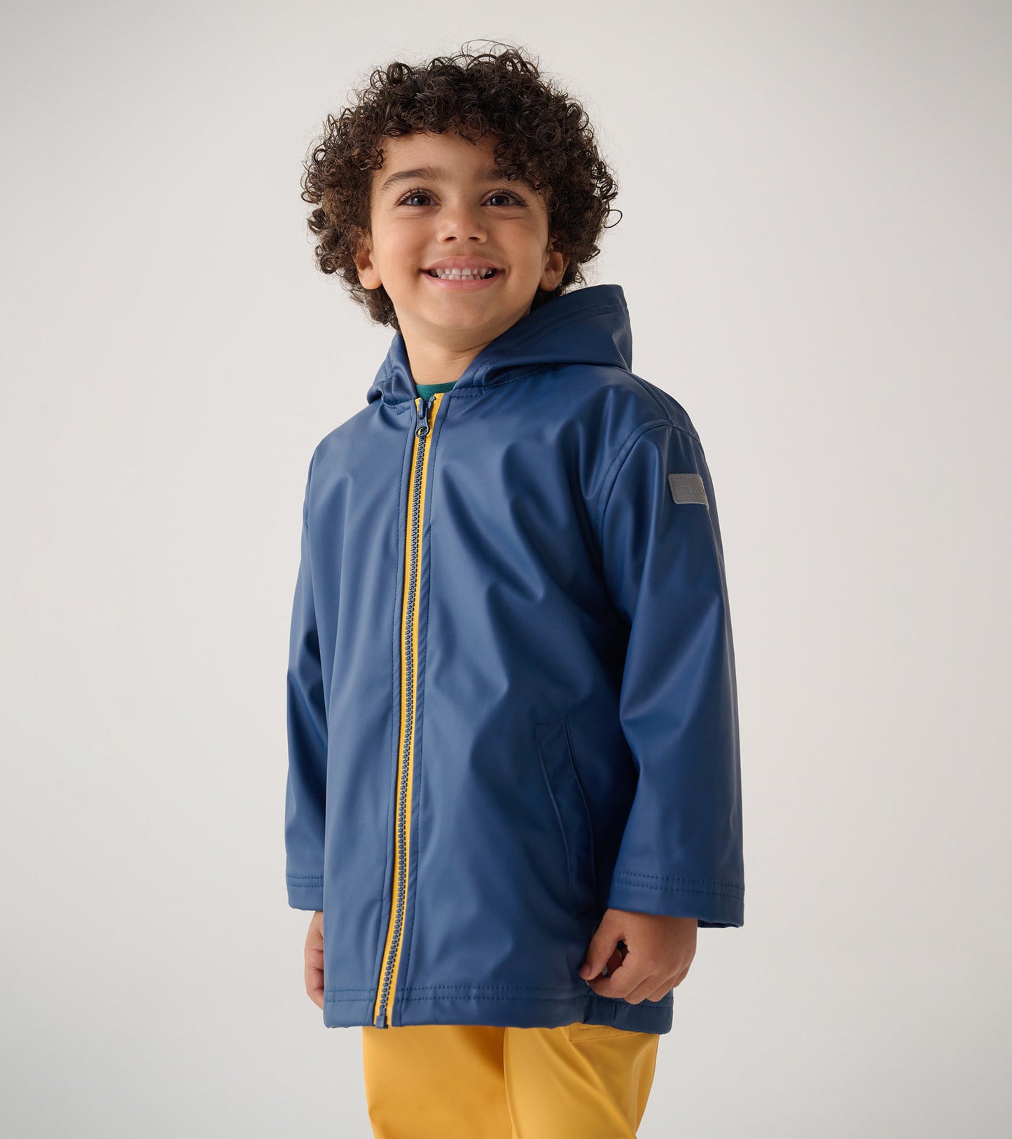 Navy zip-up rain jacket with a hood and yellow zipper, designed for kids, featuring a relaxed fit and side pockets.