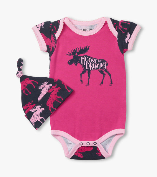 Pink baby bodysuit with moose graphic and matching hat featuring moose pattern on a navy background.