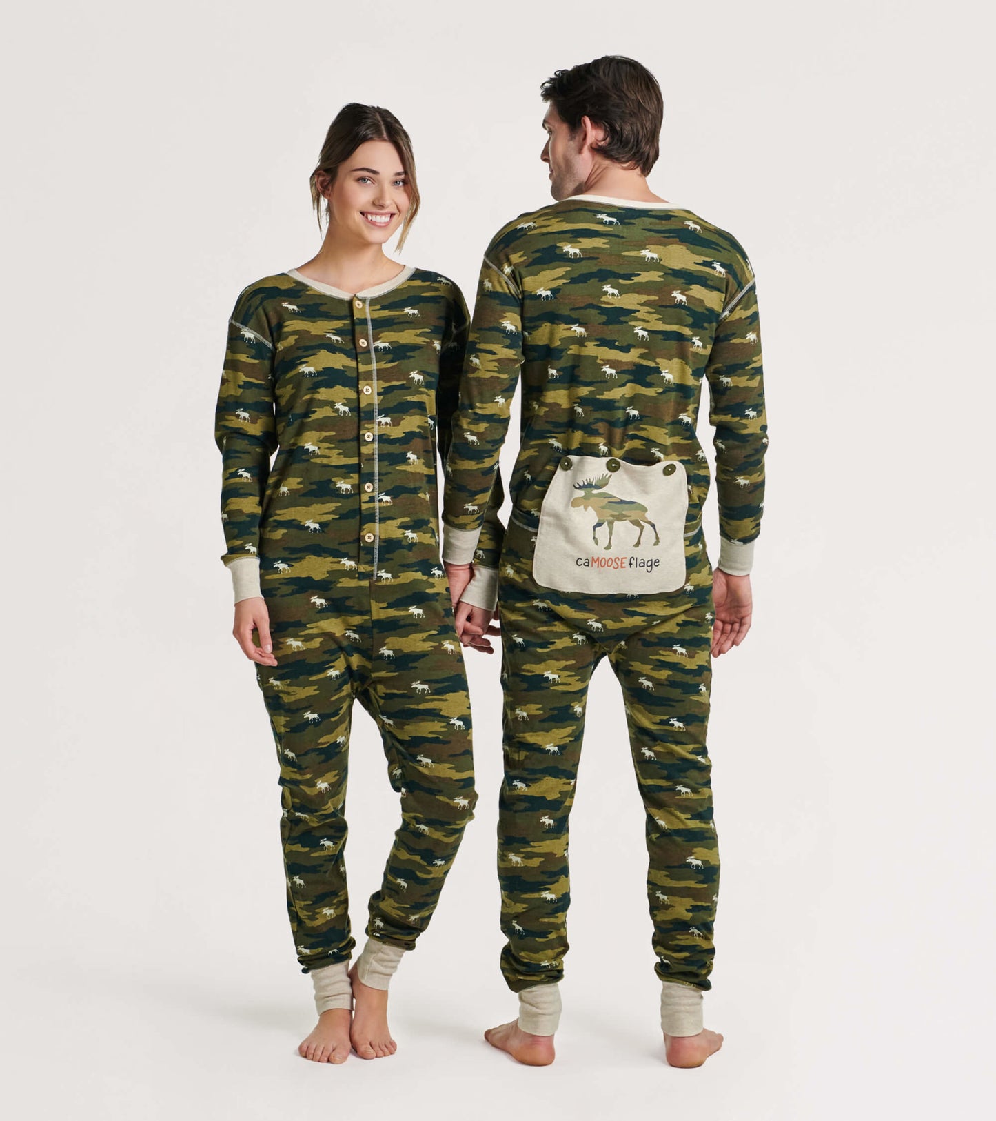 Camo-patterned adult onesie in green and brown with buttons and a moose graphic on the back, shown on two models.