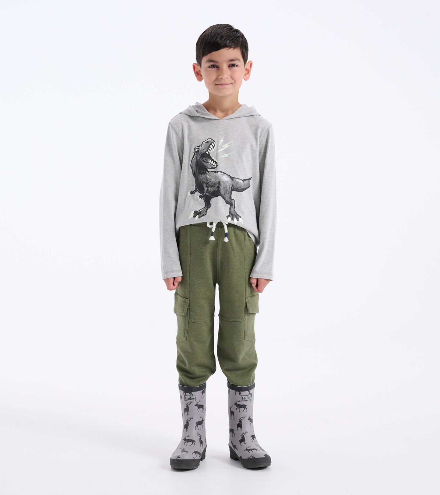 Boys' moss melange cargo joggers in soft fabric with side pockets, paired with a gray dinosaur graphic hoodie and rain boots.