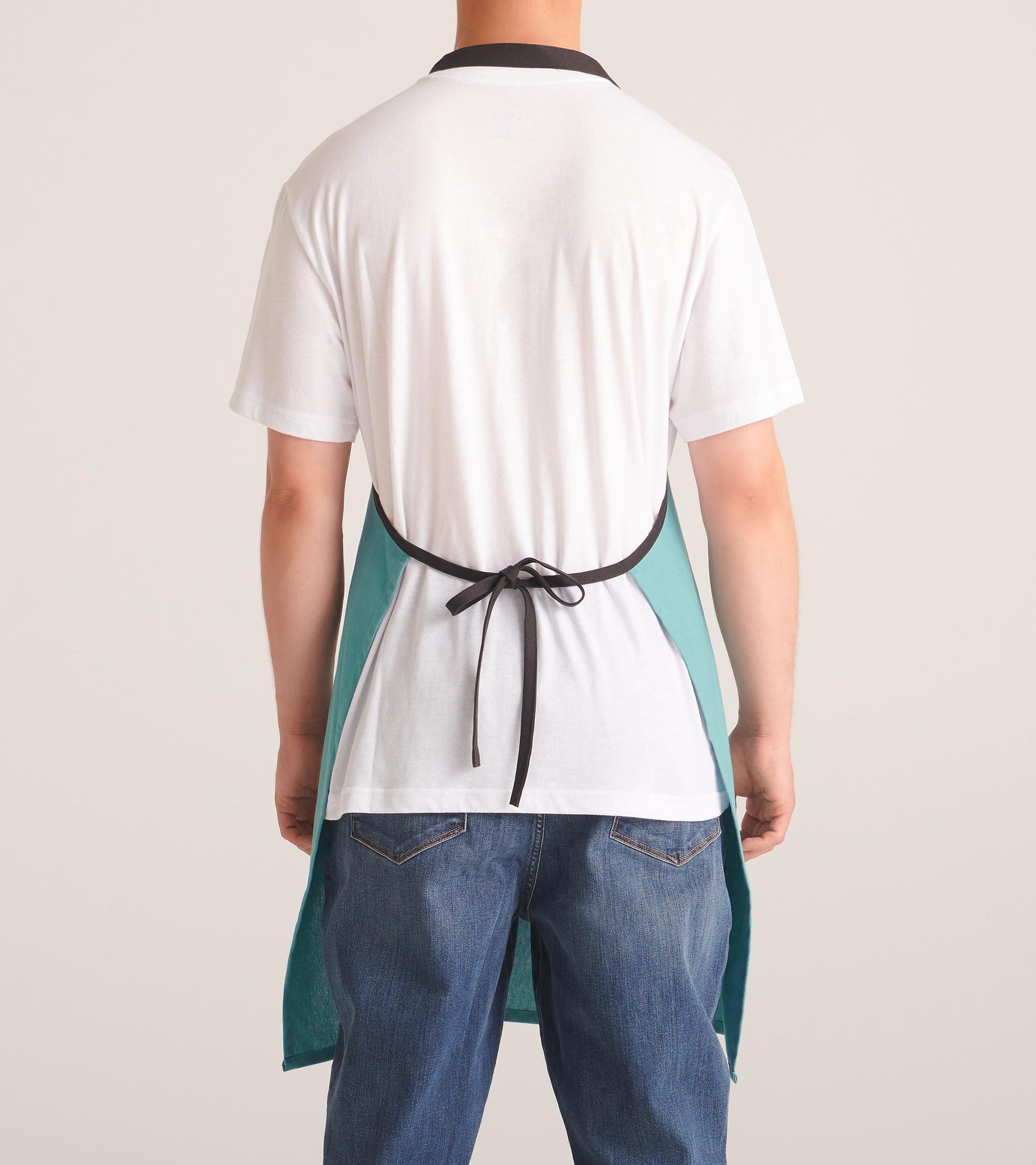 Teal apron with a black neck strap, tied at the back, worn over a white shirt and jeans.