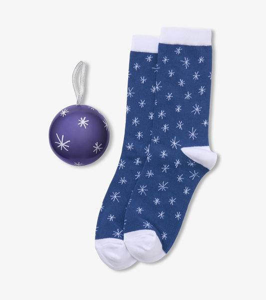 Blue snowflake crew socks with white cuffs, heels and toes beside a purple snowflake ornament