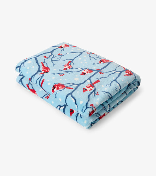 Folded fleece blanket with red cardinals, blue branches, and white snowflakes on a light blue background