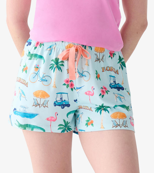 Close-up of light blue pajama shorts with coral drawstring and Florida print of flamingos, palms, gators, and golf carts