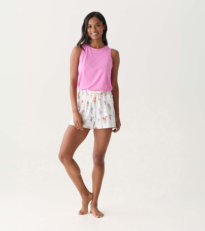 Woman wearing pink sleeveless top and white floral pajama shorts, standing front view.