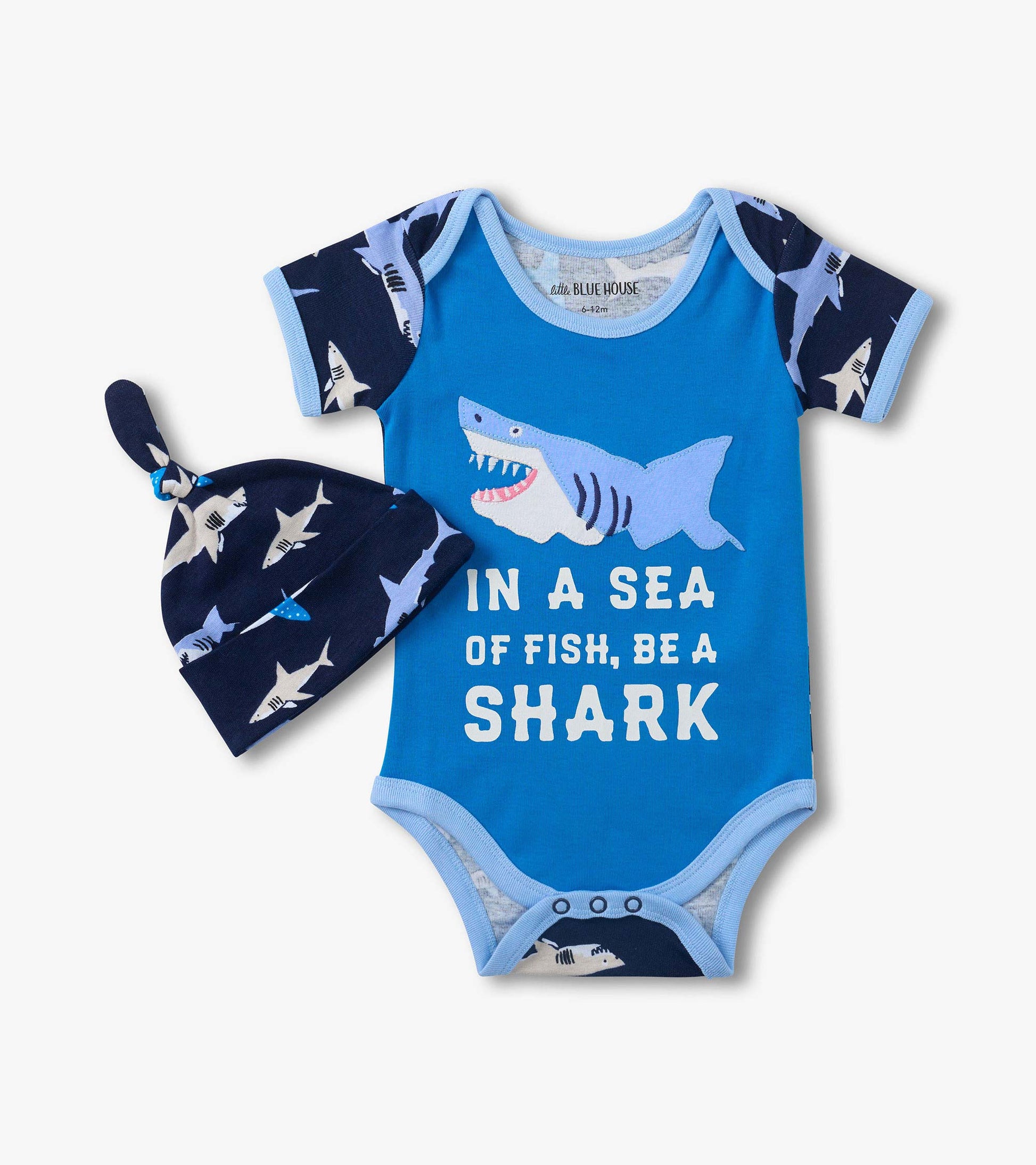 Blue baby bodysuit with shark graphic and matching navy shark-print hat, front view