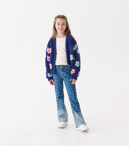 Flared leg denim for girls featuring a heart pattern in blue, paired with a cozy cardigan and white sneakers.