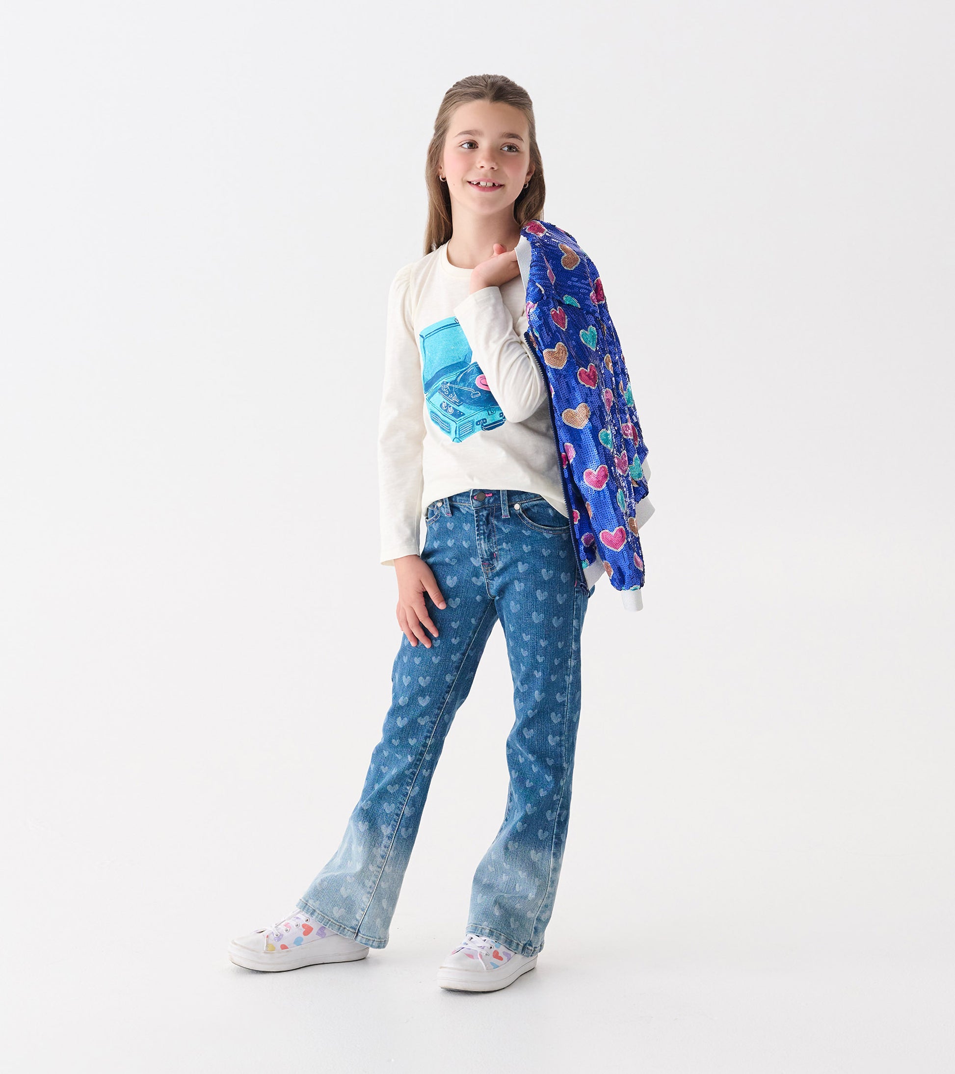Flared leg denim jeans for girls featuring a heart pattern in blue, paired with a light top and colorful shoes.