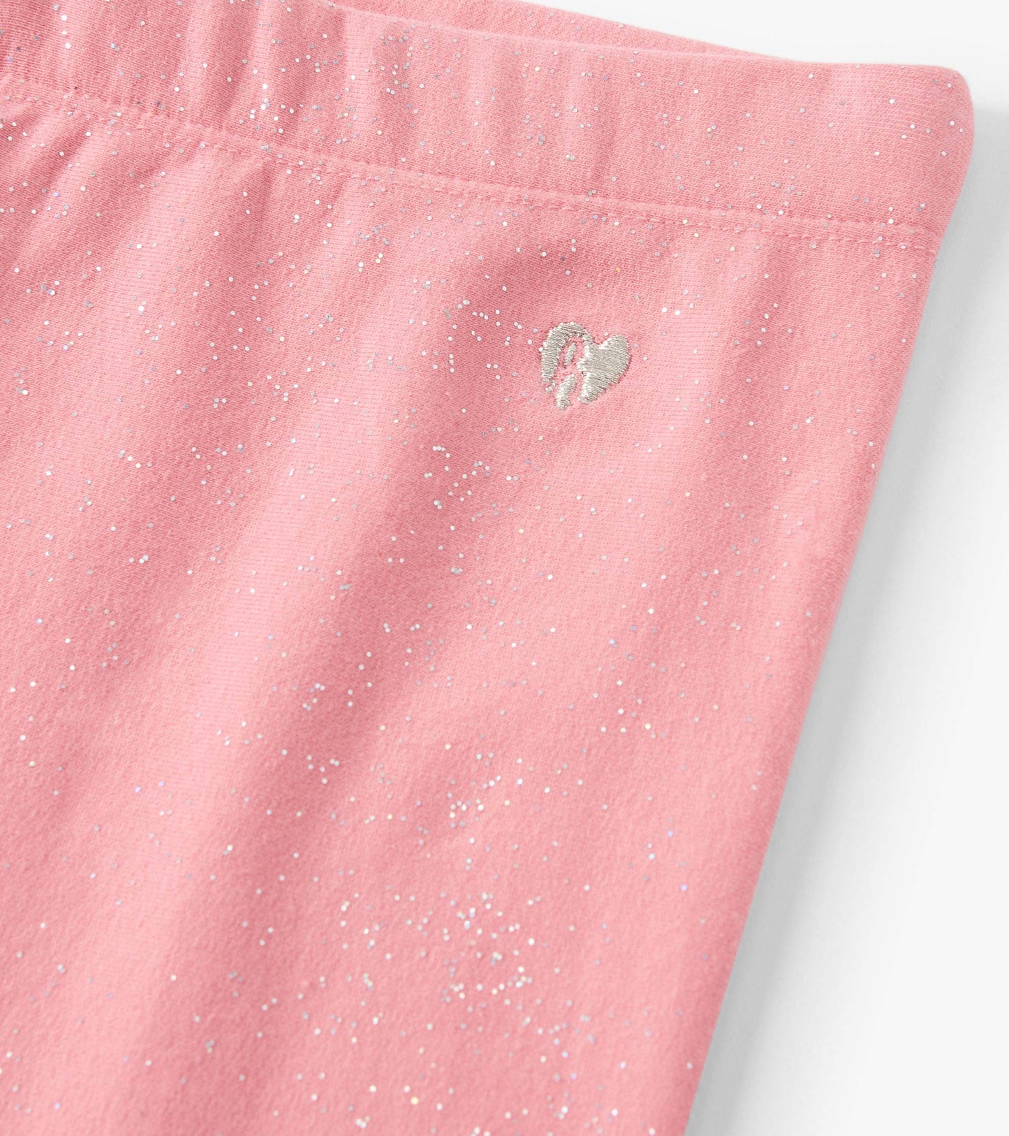 Pink cozy leggings with a sparkly pattern and a small embroidered heart detail.