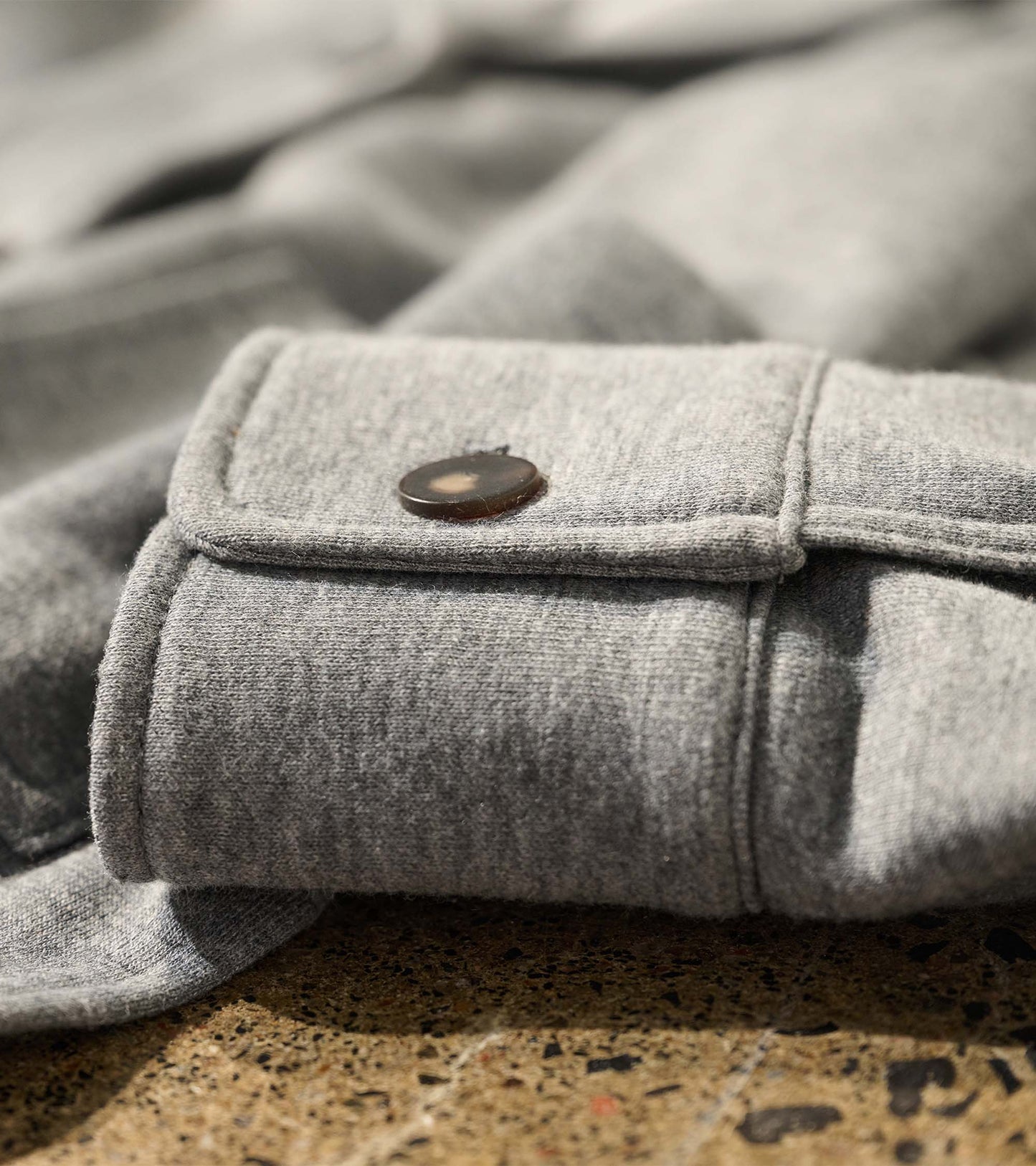 Close-up of the charcoal melange blazer sleeve cuff with a single black button tab