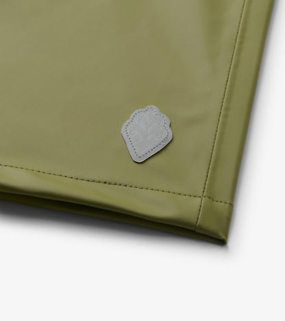 Close-up of loden green rain jacket hem with small reflective patch detail