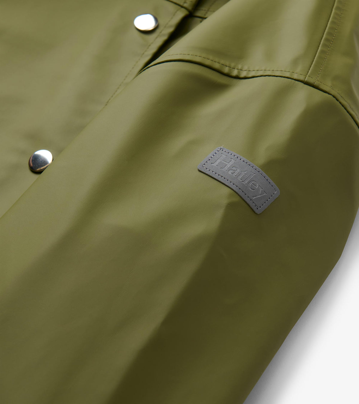 Close-up of loden green rain jacket sleeve with visible Hatley patch and silver snaps