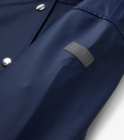 Close-up of patriot blue rain jacket sleeve with gray Hatley logo patch and silver snap