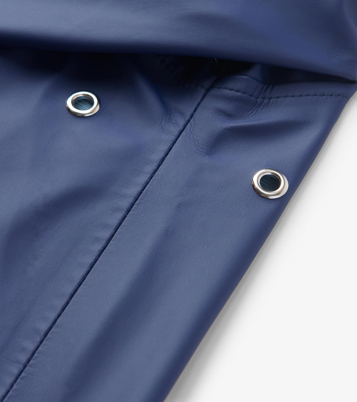 Close-up of the patriot blue rain jacket with silver grommets and a stitched seam detail.